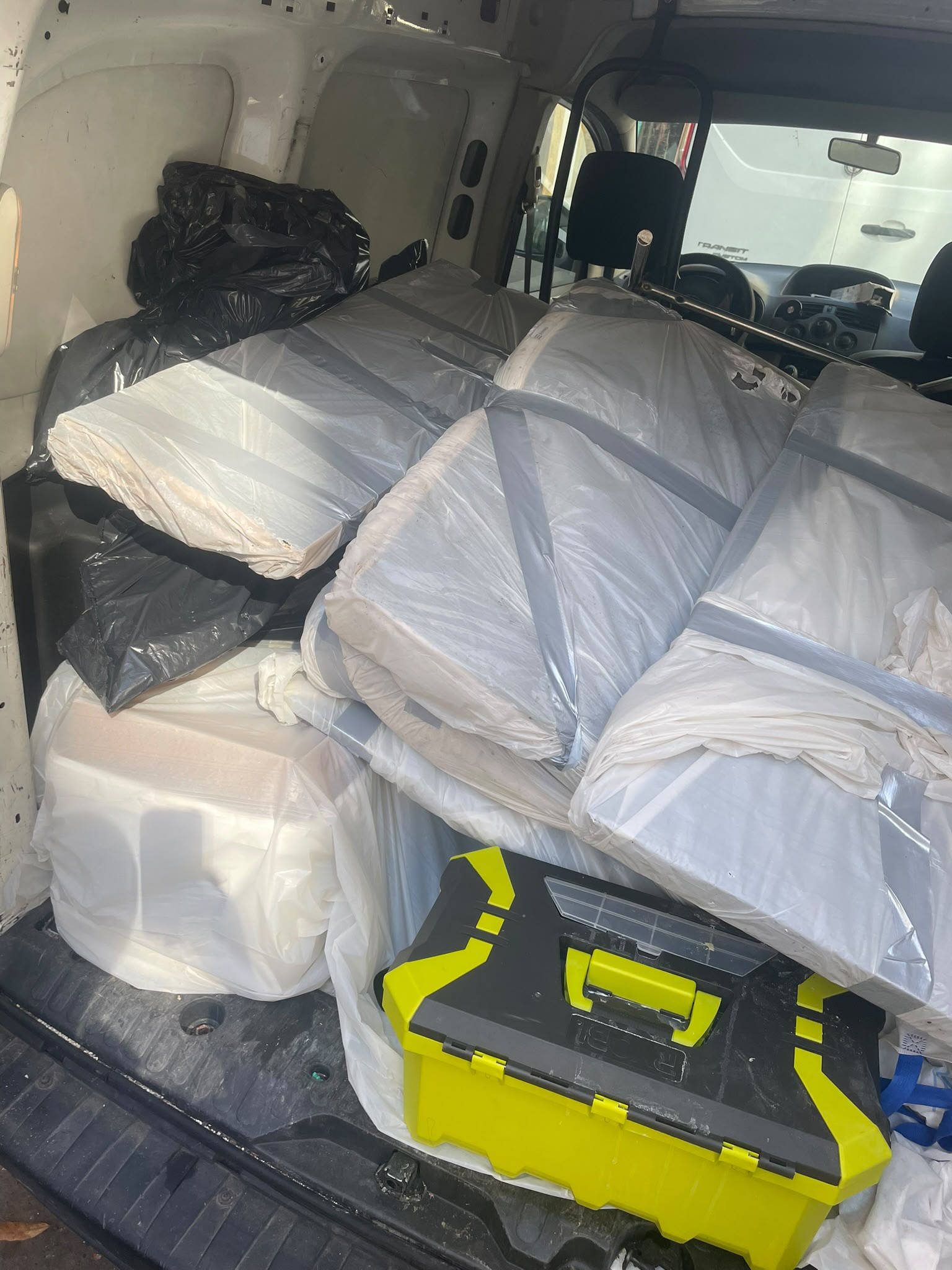 Véhicule utilitaire chargé de matelas et mobilier emballés pour évacuation après traitement anti-punaises de lit